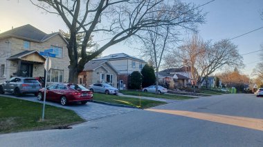 Toronto, ON, Kanada - 9 Nisan 2025: Park halindeki arabaların ve olgun ağaçların tomurcuklanmaya başladığı sakin bir yerleşim yeri..