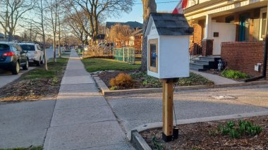 Toronto, ON, Kanada - 13 Nisan 2025: Bir yerleşim bölgesindeki kaldırım kenarında beyaz bir Serbest Kütüphane duruyor.