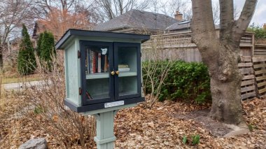 Toronto, ON, Kanada - 13 Nisan 2025: Bir yerleşim bölgesindeki kaldırım kenarında beyaz bir Serbest Kütüphane duruyor.