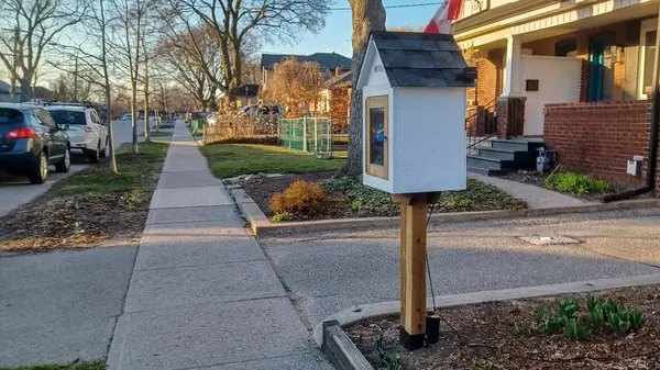 Toronto, ON, Kanada - 13 Nisan 2025: Bir yerleşim bölgesindeki kaldırım kenarında beyaz bir Serbest Kütüphane duruyor.