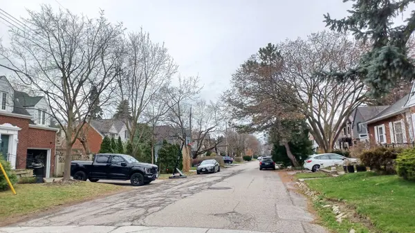 Toronto, ON, Kanada - 9 Nisan 2025: Park halindeki arabaların ve olgun ağaçların tomurcuklanmaya başladığı sakin bir yerleşim yeri..
