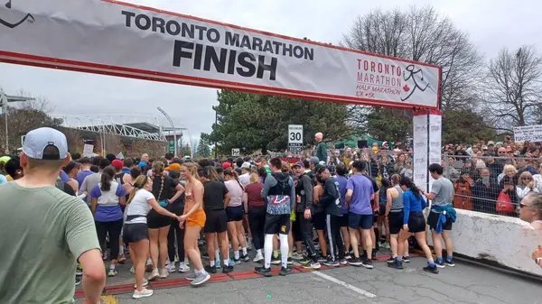 Toronto, ON, Kanada - 29 Nisan 2025: Toronto Maratonu bitiş çizgisinde büyük bir koşucu grubu toplanıyor. Çok sayıda koşucu ve dar yol geçişi imkansız kılıyor..