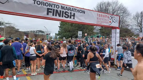 Toronto, ON, Kanada - 29 Nisan 2025: Toronto Maratonu bitiş çizgisinde büyük bir koşucu grubu toplanıyor. Çok sayıda koşucu ve dar yol geçişi imkansız kılıyor..