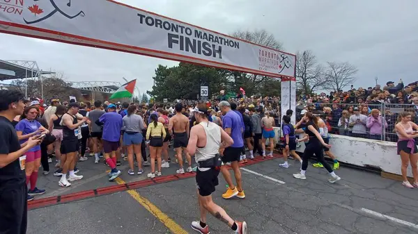 Toronto, ON, Kanada - 29 Nisan 2025: Toronto Maratonu bitiş çizgisinde büyük bir koşucu grubu toplanıyor. Çok sayıda koşucu ve dar yol geçişi imkansız kılıyor..