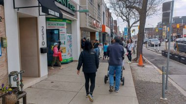 Toronto, ON, Kanada - 14 Nisan 2025: İnsanlar Durie Caddesi yakınlarındaki Bloor Caddesi boyunca 9 bahar öğleden sonra bulutlu bir gökyüzü altında yürüyüp alışveriş yapıyorlar.