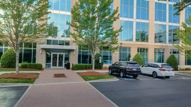 Charlotte, NC, ABD 29 Nisan 2025: Modern bir bina lobisi cam duvarlardan ağaçlara ve açık hava manzarasına bakıyor..