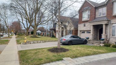 Toronto, ON, Kanada - 9 Nisan 2025: Park halindeki arabaların ve olgun ağaçların tomurcuklanmaya başladığı sakin bir yerleşim yeri..