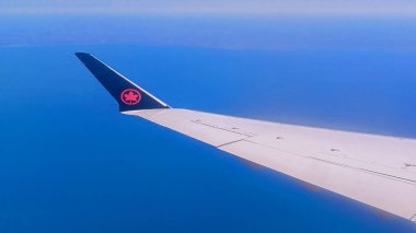 Toronto, ON, Kanada - 1 Mayıs 2025: Air Canada akçaağaç yaprağı logosuna sahip kanat ve kuyruk yüzgeci uçuş sırasında bir bulut katmanının üzerinde görünür..