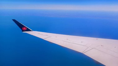 Toronto, ON, Kanada - 1 Mayıs 2025: Air Canada akçaağaç yaprağı logosuna sahip kanat ve kuyruk yüzgeci uçuş sırasında bir bulut katmanının üzerinde görünür..
