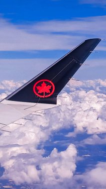Toronto, ON, Kanada - 1 Mayıs 2025: Air Canada akçaağaç yaprağı logosuna sahip kanat ve kuyruk yüzgeci uçuş sırasında bir bulut katmanının üzerinde görünür..