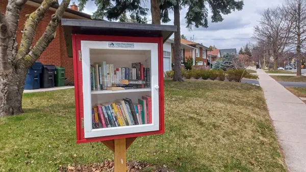 Toronto, ON, Kanada - 13 Nisan 2025: Bir yerleşim bölgesindeki kaldırım kenarında beyaz bir Serbest Kütüphane duruyor.