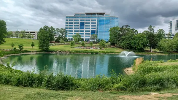 Charlotte, NC, ABD - 30 Nisan 2025: Modern ofis binaları yeşil çimenlerin, ağaçların ve Ballantyne Corporate Park 'ta bulutlu bir gökyüzünün altında bir yürüyüş yolunun ortasında duruyor.