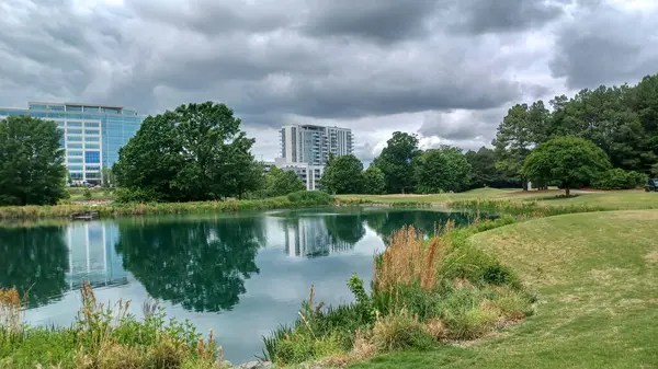 Charlotte, NC, ABD - 30 Nisan 2025: Modern ofis binaları yeşil çimenlerin, ağaçların ve Ballantyne Corporate Park 'ta bulutlu bir gökyüzünün altında bir yürüyüş yolunun ortasında duruyor.