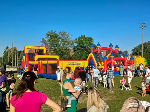 Toronto, ON, Kanada 31 Mayıs 2024: Aileler güneşli bir öğleden sonra bir çocuk etkinliğinde büyük şişme slaytlar ve engelli parkurların etrafında toplandılar..