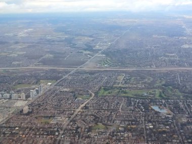 Toronto, Kanada 26 Kasım 2024: Toronto banliyölerinin hava görüntüsü dramatik bulutlar altında bir Air Transat uçağı kalkıştan sonra yükseliyor..