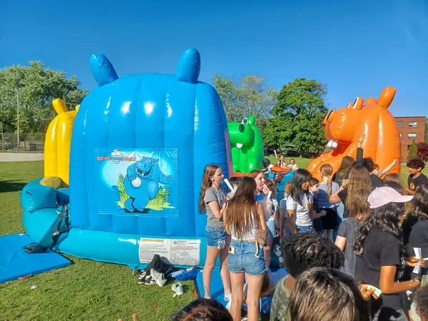 Toronto, ON, Kanada 31 Mayıs 2024: Aileler güneşli bir öğleden sonra bir çocuk etkinliğinde büyük şişme slaytlar ve engelli parkurların etrafında toplandılar..