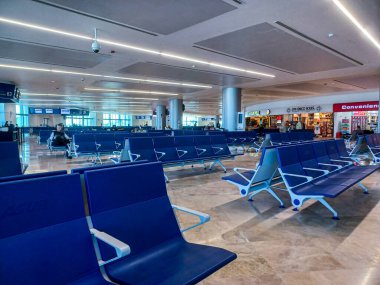 Cancun, Quintana Roo, Meksika 26 Kasım 2024: Gezginler Cancun Uluslararası Havaalanı 'ndaki dükkanların yakınındaki oturma alanında oturup bekliyorlar..