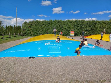 Toronto, Kanada 1 Eylül 2024: Çocuklar ve ebeveynler Downey Çiftliği 'nde açık mavi bir gökyüzü altında renkli şişme yastıklarda oynuyorlar..