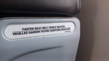 Charlotte, NC, ABD, 30 Nisan 3025: Bir uçak koltuğunun yanında İngilizce ve Fransızca bir levhada 