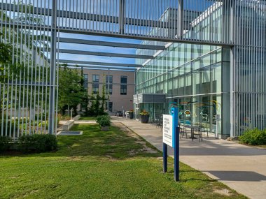 Toronto, ON, Kanada 2 Temmuz 2024: Humber Üniversitesi manzaralı Lakeshore kampüsünde ağaçlar ve yeşil çimlerle çevrili modern bir cam bina bulunuyor..