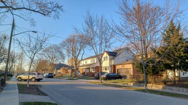 Toronto, ON, Kanada - 9 Nisan 2025: Park halindeki arabaların ve olgun ağaçların tomurcuklanmaya başladığı sakin bir yerleşim yeri..