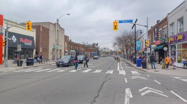Toronto, ON, Kanada - 14 Nisan 2025: İnsanlar Durie Caddesi yakınlarındaki Bloor Caddesi boyunca 9 bahar öğleden sonra bulutlu bir gökyüzü altında yürüyüp alışveriş yapıyorlar.