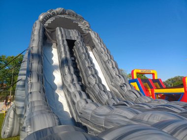 Toronto, ON, Kanada 31 Mayıs 2024: Aileler güneşli bir öğleden sonra bir çocuk etkinliğinde büyük şişme slaytlar ve engelli parkurların etrafında toplandılar..