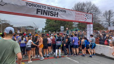 Toronto, ON, Kanada - 29 Nisan 2025: Toronto Maratonu bitiş çizgisinde büyük bir koşucu grubu toplanıyor. Çok sayıda koşucu ve dar yol geçişi imkansız kılıyor..
