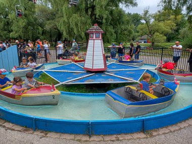 Toronto, ON, Kanada 08 Ağustos 2024: Çocuklar Centerville Lunaparkı 'nda küçük motorlu teknelere binerken ebeveynler de yakınlarda seyrediyorlar...