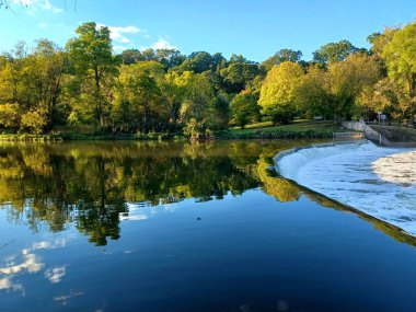 Akşam güneşi Humber Nehri somon merdivenini aydınlatıyor. İnsanlar nehir boyunca toplanıp akan suyu seyrediyorlar..