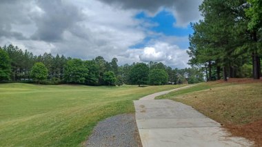 Charlotte, NC, ABD - 30 Nisan 2025: Modern ofis binaları yeşil çimenlerin, ağaçların ve Ballantyne Corporate Park 'ta bulutlu bir gökyüzünün altında bir yürüyüş yolunun ortasında duruyor.