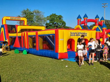 Toronto, ON, Kanada 31 Mayıs 2024: Aileler güneşli bir öğleden sonra bir çocuk etkinliğinde büyük şişme slaytlar ve engelli parkurların etrafında toplandılar..