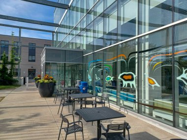 Toronto, ON, Kanada 2 Temmuz 2024: Humber Üniversitesi manzaralı Lakeshore kampüsünde ağaçlar ve yeşil çimlerle çevrili modern bir cam bina bulunuyor..