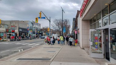 Toronto, ON, Kanada - 14 Nisan 2025: İnsanlar Durie Caddesi yakınlarındaki Bloor Caddesi boyunca 9 bahar öğleden sonra bulutlu bir gökyüzü altında yürüyüp alışveriş yapıyorlar.