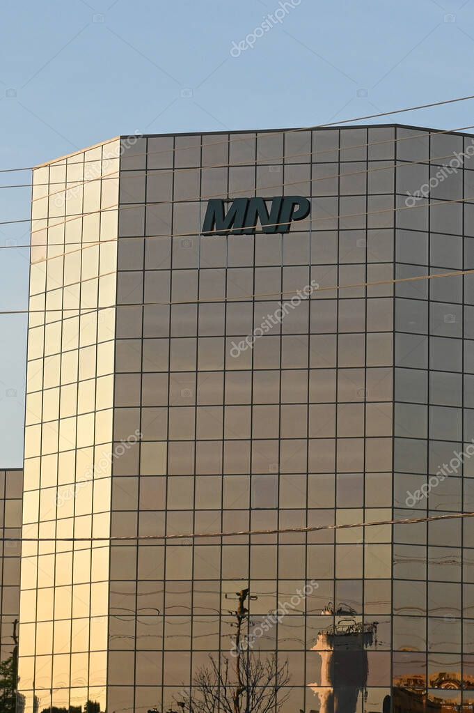 Calgary, AB, Canada - September 18, 2025: A sleek glass tower displays the MNP logo and Canadian flag against a clear blue sky.