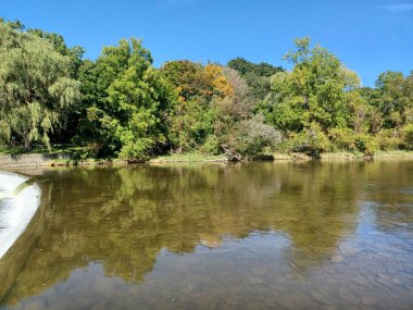 Akşam güneşi Humber Nehri somon merdivenini aydınlatıyor. İnsanlar nehir boyunca toplanıp akan suyu seyrediyorlar..