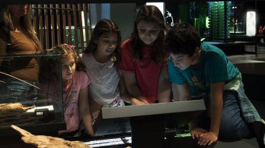 Ergenlik öncesi öğrencilerden oluşan bir grup merak uyandırıcı bir şekilde ekrana takım olarak bakıyorlar..