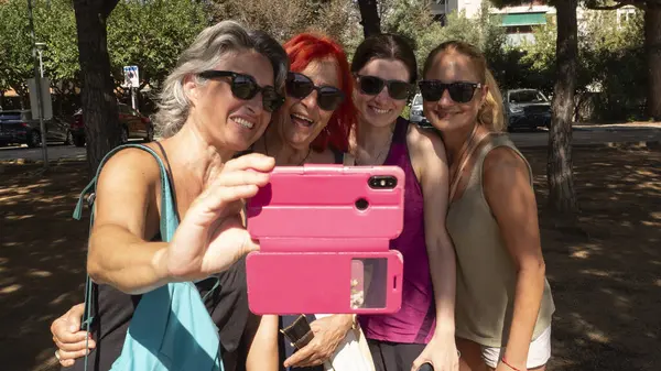 Group of 4 women, take a selfie looking at the camera and smiling, funny attitude, different coloured hair, family, generation of women.
