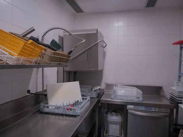 cleaning room, work space with industrial dishwasher, kitchen office, open dishwasher waiting for the next wash, you can see a cutting board and a knife for washing, the dishwasher is with a trolley full of dishes and tapers already washed and clean.