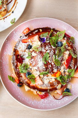 Taze ev yapımı waffle tabağının üst görüntüsü. Dondurma, karamel sosu ve ahşap masadaki waffle 'ların üstünde taze böğürtlen.