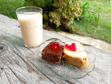 Frenk üzümlü bir parça kek ve ahşap zemin üzerinde bir bardak süt.