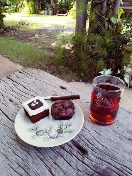 a closeup shot of a delicious cake and a glass of tea on a wooden table
