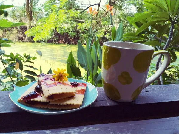 a piece of cake with a cup of coffee and a cake on a wooden table