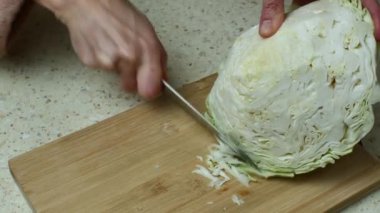 Parlak bir mutfak masasında, keskin bir bıçakla beyaz lahana doğrayan bir kadın. Ev hanımı sebze salatası hazırlamak için lahana keser. Vigaterian beslenme. Sağlıklı yemek..