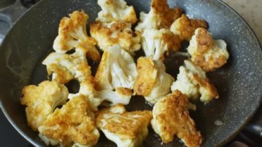 Üzerinde çırpılmış yumurta hamuru olan karnabahar parçalarıyla yakın çekim. Kızarmış karnabahar haşlanmış sebze yağı, yağ cızırtısı ve kabarcıklarla tavada kızartılır. Sağlıklı bitki yiyeceği