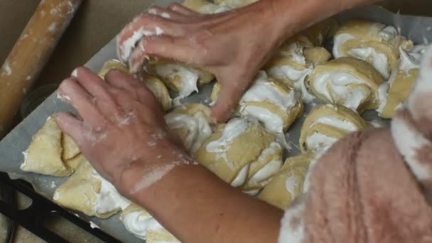 羊皮紙で覆われたベーキングシートにオーブンで焼くための白いクリームとケーキを敷設女性の手のクローズアップ おいしい自家製ケーキ 手作り菓子のためのステップバイステップのレシピ — ストック動画
