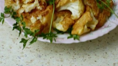 Yemek masasında servis edilen kadın elleri hamurda kızartılmış karnabahar ve yakın plan yeşillikler serpiştirilmiş. Seçici odaklanma Lezzetli ve sağlıklı sebze yemekleri