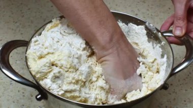 Demir tavada taze hamur yoğuran ev kadınlarının yakın çekimi. Bir eliyle, kadın bir tava tutuyor ve diğer eliyle beyaz undan buğday hamuru yoğuruyor geleneksel ev yapımı ekmek pişiriyor..