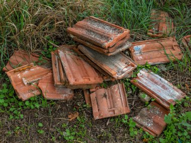 Bir yığın eski, kirli, kırık kiremit. Eski çatı kiremitleri yere yığılmış. Tamir konsepti, evin çatısındaki eski fayansların değiştirilmesi.