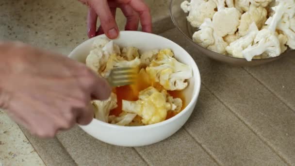 被打坏的鸡蛋和花椰菜片与叉子一起在白玻璃碗里搅拌 准备进一步烹调 将几片花椰菜放入一个装有打蛋的碗中 — 图库视频影像